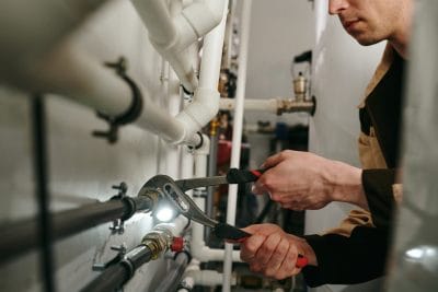 Technician inspecting commercial plumbing pipes in Seal Beach